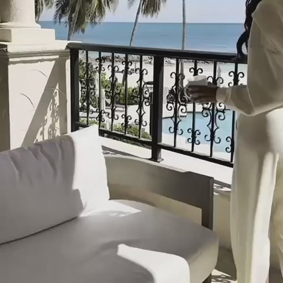 امرأة تجلس على شرفة فاخرة بإطلالة بحرية هادئة في أجواء استرخاء وأناقة
